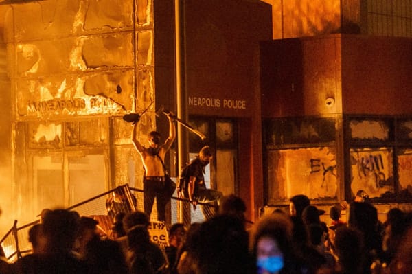 Rioters in the foreground, standing before the burning 3rd precinct in Minneapolis